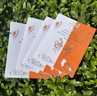 four orange and white booklets on a green grass