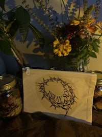 a bag with a crown of thorns on it next to a vase of flowers
